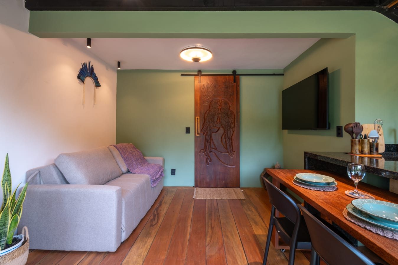Sala com sofá e porta entalhada de araras