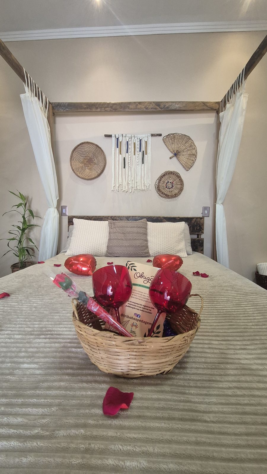 Cesta de boas-vindas com taças e rosa sobre a cama